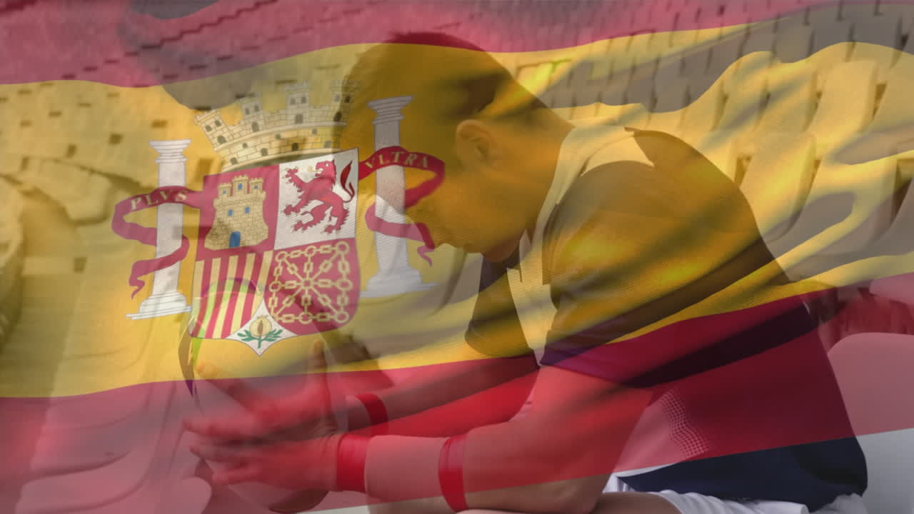 Animation of spanish flag waving over sad caucasian male player sitting on chair in empty stadium