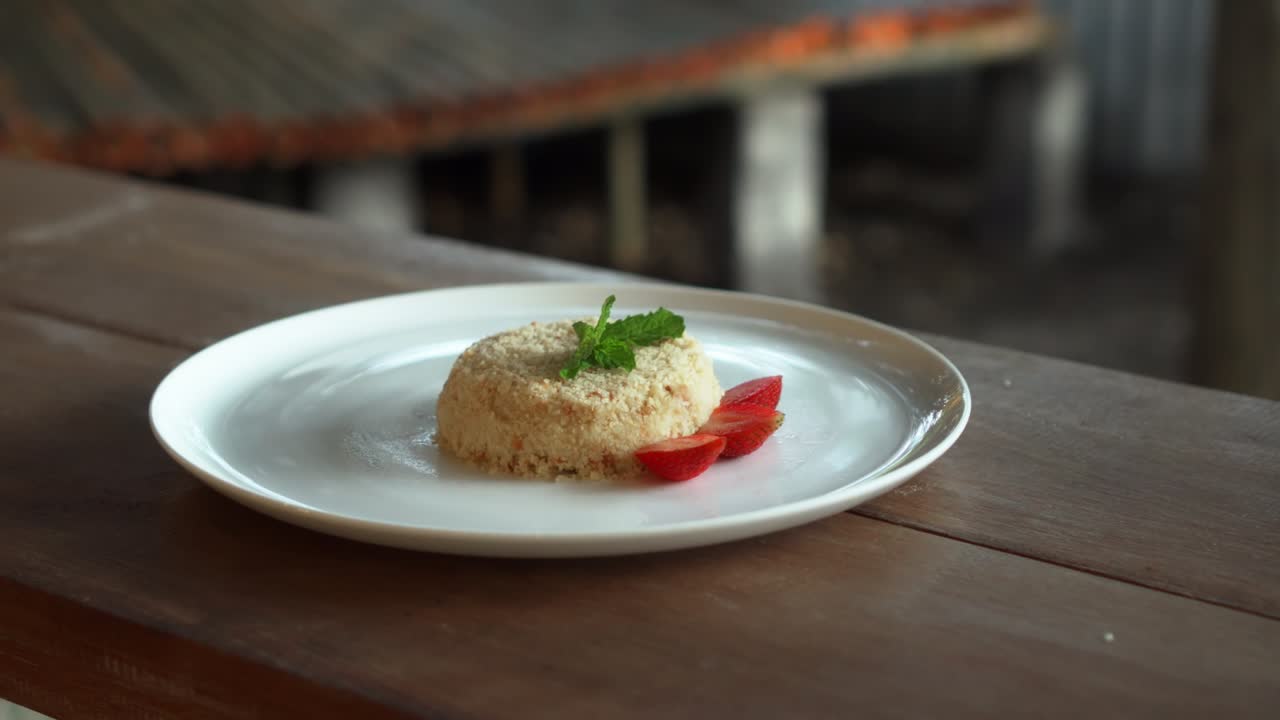 Piccola torta millefoglie con fragole sopra, su un piatto bianco