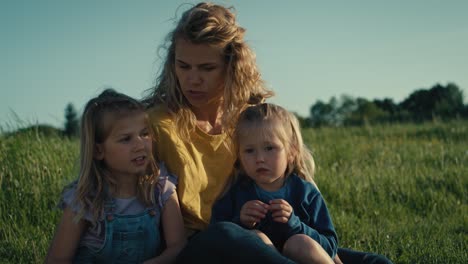 mom with two little daughters bonding and spending time together at the meadow.