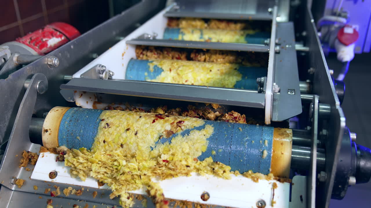 Rotating shafts transporting mashed apples pulp. Conveyor line at the factory producing organic apple juice fruit.