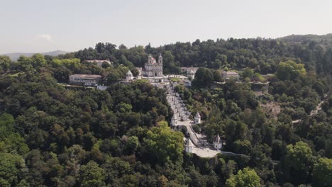 antena orbitando sobre el lugar de peregrinación cristiana, el monte bom jesus rodeado de bosque - braga