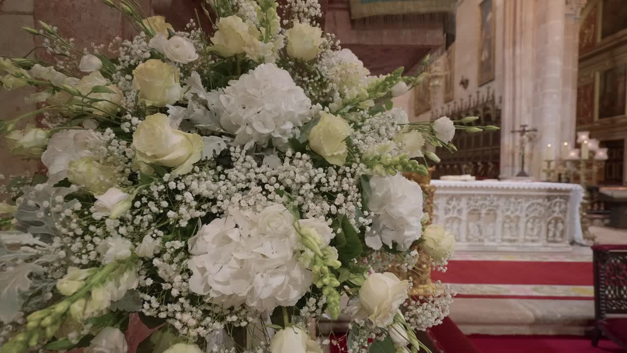 Elegante composizione floreale bianca con rose e ortensie disposta vicino all'altare all'interno della cattedrale Sé de Braga, Portogallo