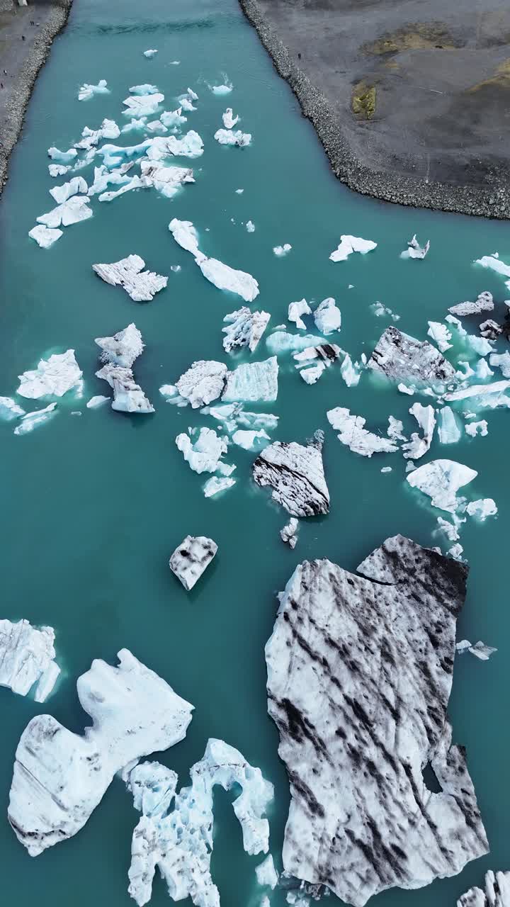 Aerial drone footage view looking down on the Jökulsárlón lake of icebergs in Iceland, vertical video.