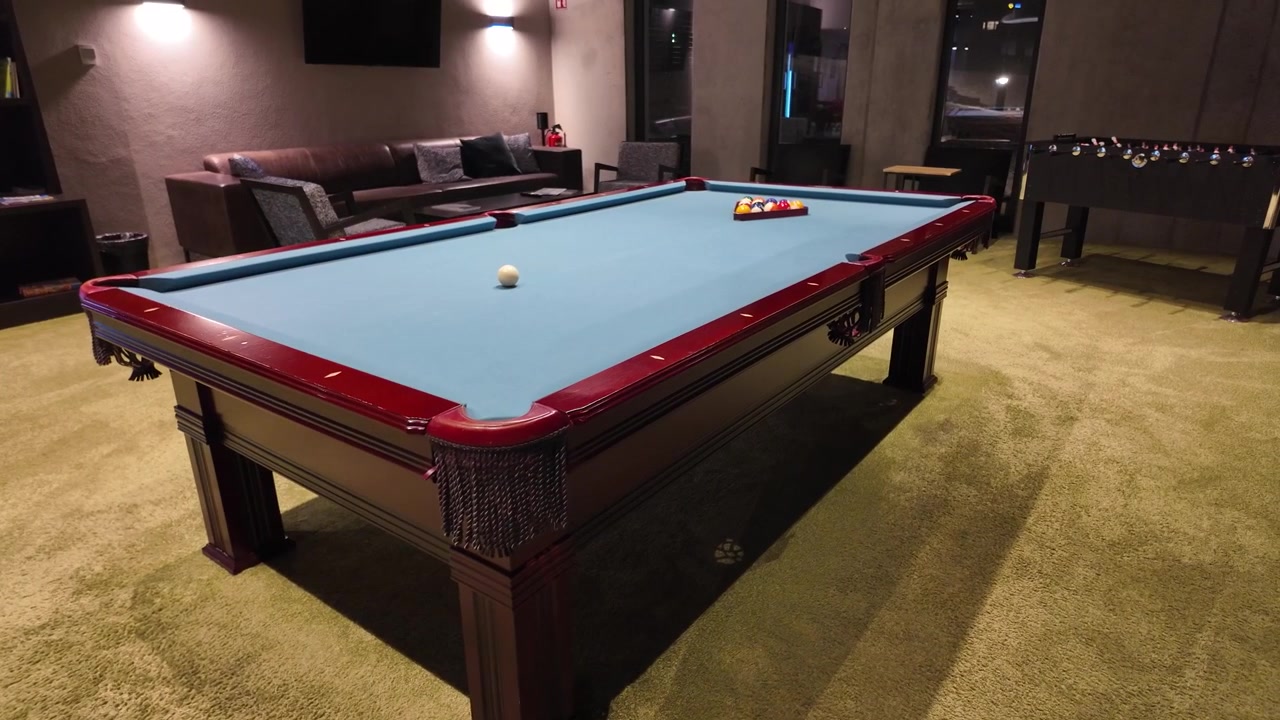 Pool table in a cozy room with sofas and armchairs, featuring neatly arranged balls on the table