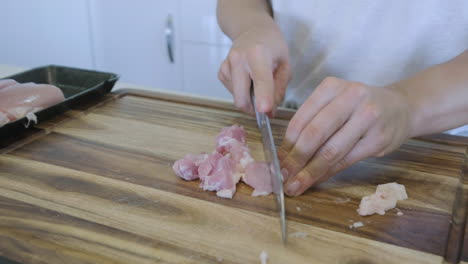 cutting up raw chicken breast to prepare for dinner