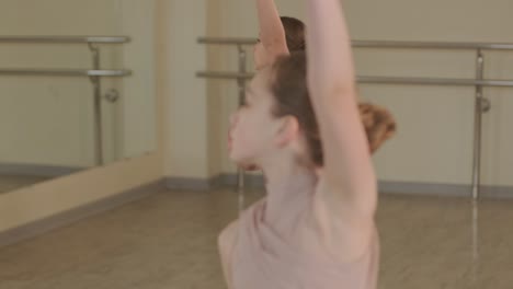 un grupo de jóvenes estudiantes de ballet con ropa de baile negra practicando posiciones en un amplio estudio de ballet con pisos de madera y barras montadas en la pared. expresiones enfocadas y movimientos sincronizados.