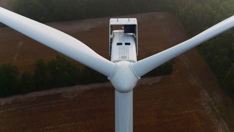 el tiro aéreo de la turbina eólica se inclina hacia abajo sobre las palas de la hélice con tierras de cultivo en el fondo