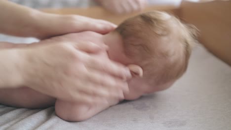 infant-boy-with-short-blond-hair-lies-on-special-table