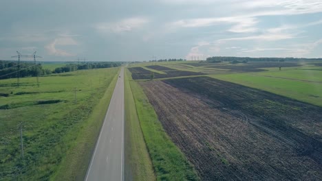 bird-eye-flight-car-drives-along-gray-road-under-summer-sky