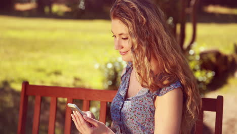 In-high-quality-4k-format-pretty-blonde-using-phone-in-the-park