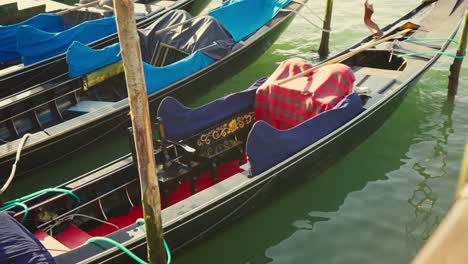 Gondolas,-typical-boats-from-Venice,-moving-on-the-water-in-the-lagoon-near-the-main-square