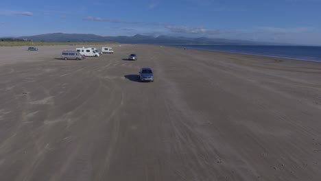 conducir un automóvil en una playa de arena de roca negra en el norte de gales