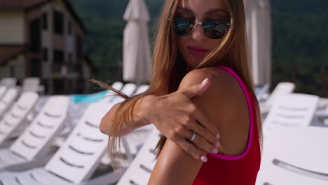 mujer aplicando protector solar en un complejo junto a la piscina