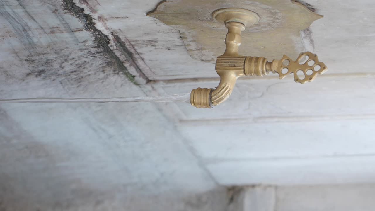 Water flowing from an antique brass faucet