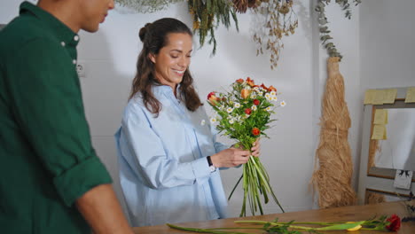 excited florist make bouquet composition in plant shop. african guy buy flowers.