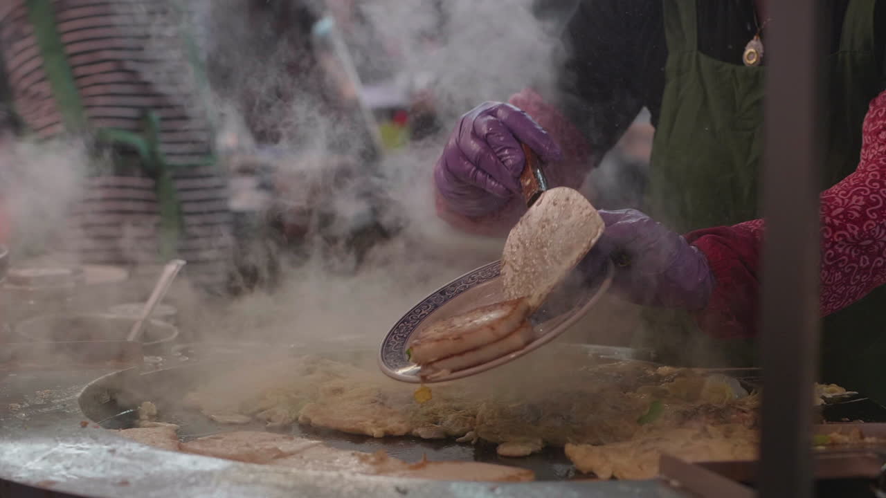 Street vendor in Taiwan at a popular night market flips turnip cakes over a large fire. Slow motion footage.
