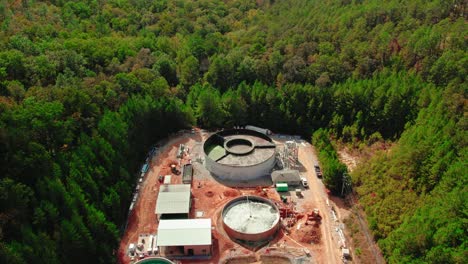 vuelo aéreo sobre una planta de tratamiento de agua en construcción rodeada de denso bosque en chelsea, alabama