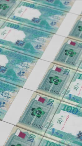 video vertical de billetes de 100 riyales qataríes impresos por una prensa de dinero