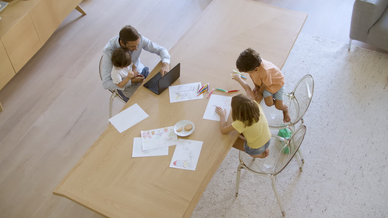 padre sosteniendo a su hijo en el regazo mientras usa una computadora portátil