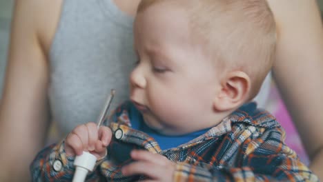 baby plays with glass dropper sitting with mother in room