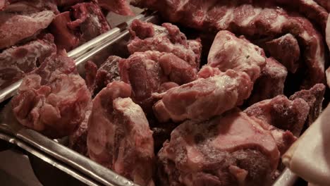 pieces-of-pork-leg-exhibited-in-butcher-shop-in-metal-container