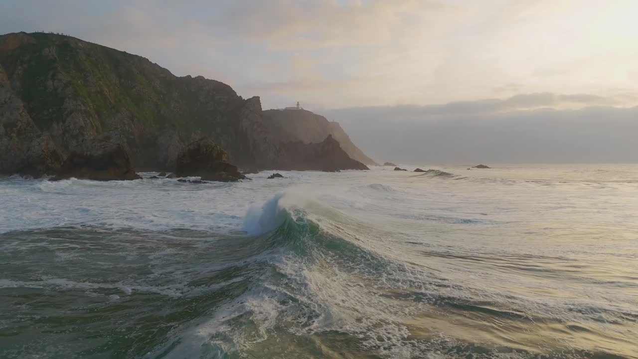 las olas del océano aplastando acantilados remotos al atardecer