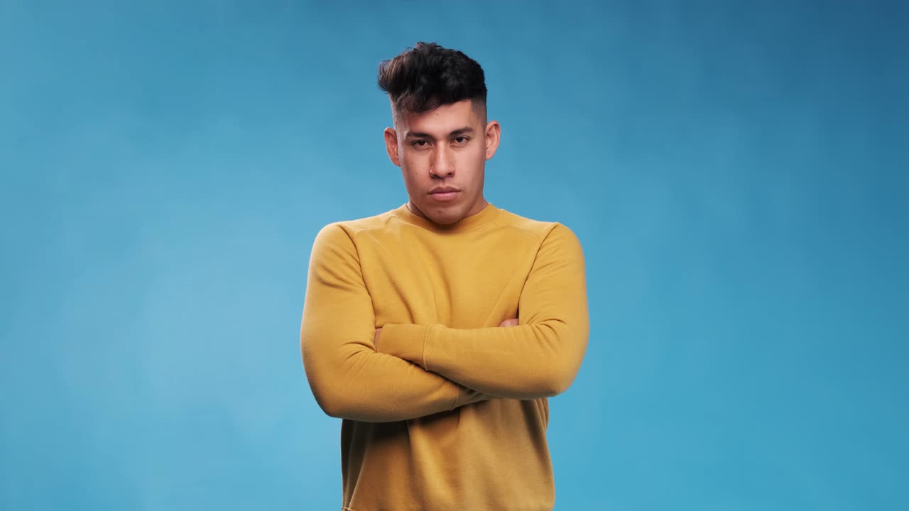 Serious and displeased man looking at camera and shakes head to disagree while standing with his arms crossed.