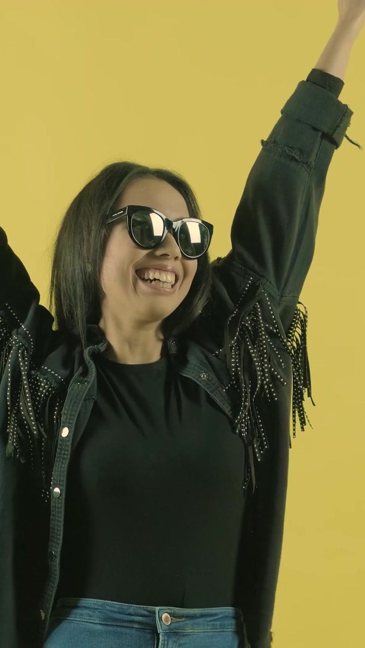 Giovane donna felice che celebra il successo su sfondo giallo