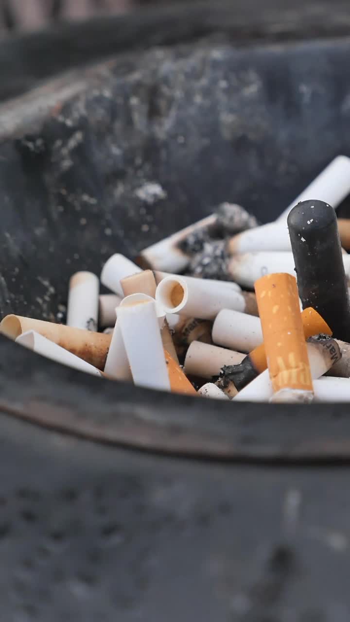 Primer Plano de Numerosas Colillas de Cigarrillos en un Cenicero Sucio