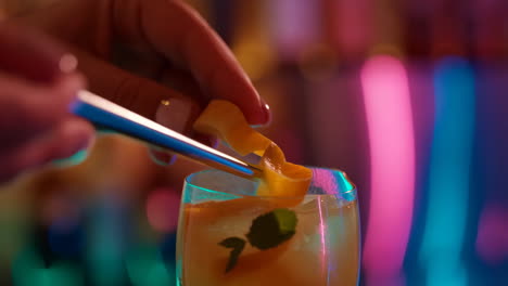 preparing a cocktail with orange peel garnish