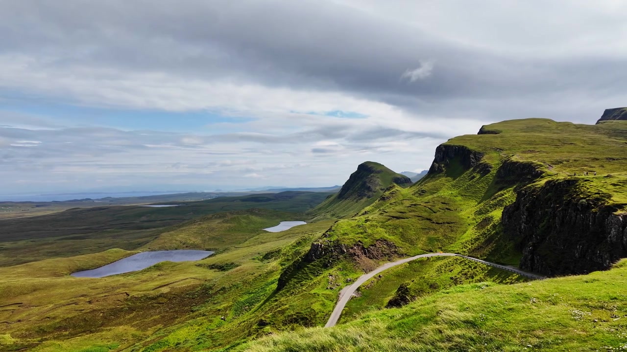 Smuk panorering af en stor grøn dal set fra Quiraing-bjerget på Isle of Skye, Skotland, på en solrig sommerdag.