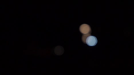 faros de coche fuera de foco, bolas de bokeh en movimiento, noche