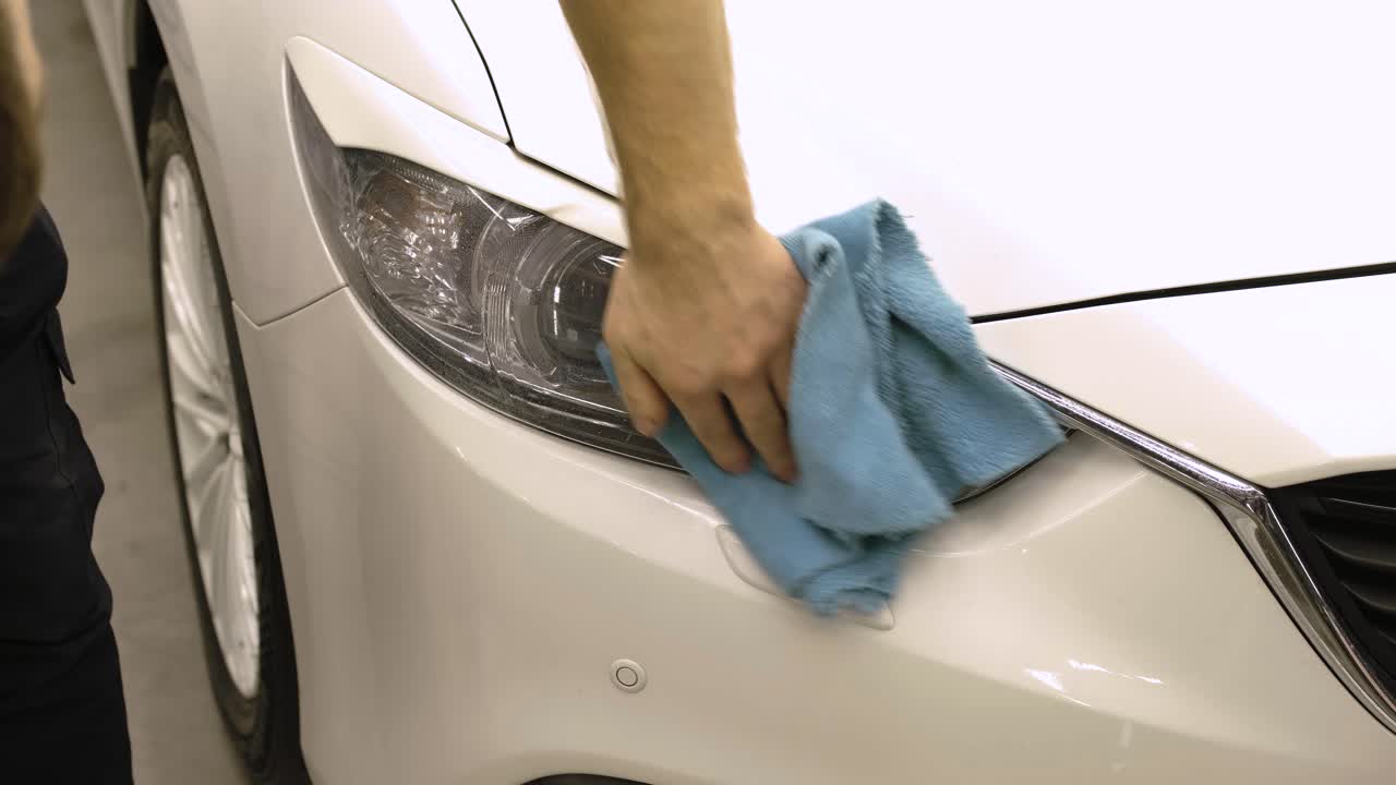 hombre cubriendo el coche con cinta de poliuretano de vinilo. películas para el coche. pegatina película protectora en el faro del coche