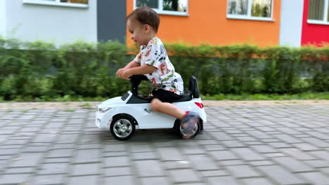 beautiful baby boy riding quickly a toy car. happy healthy kid having fun outdoors in summer.