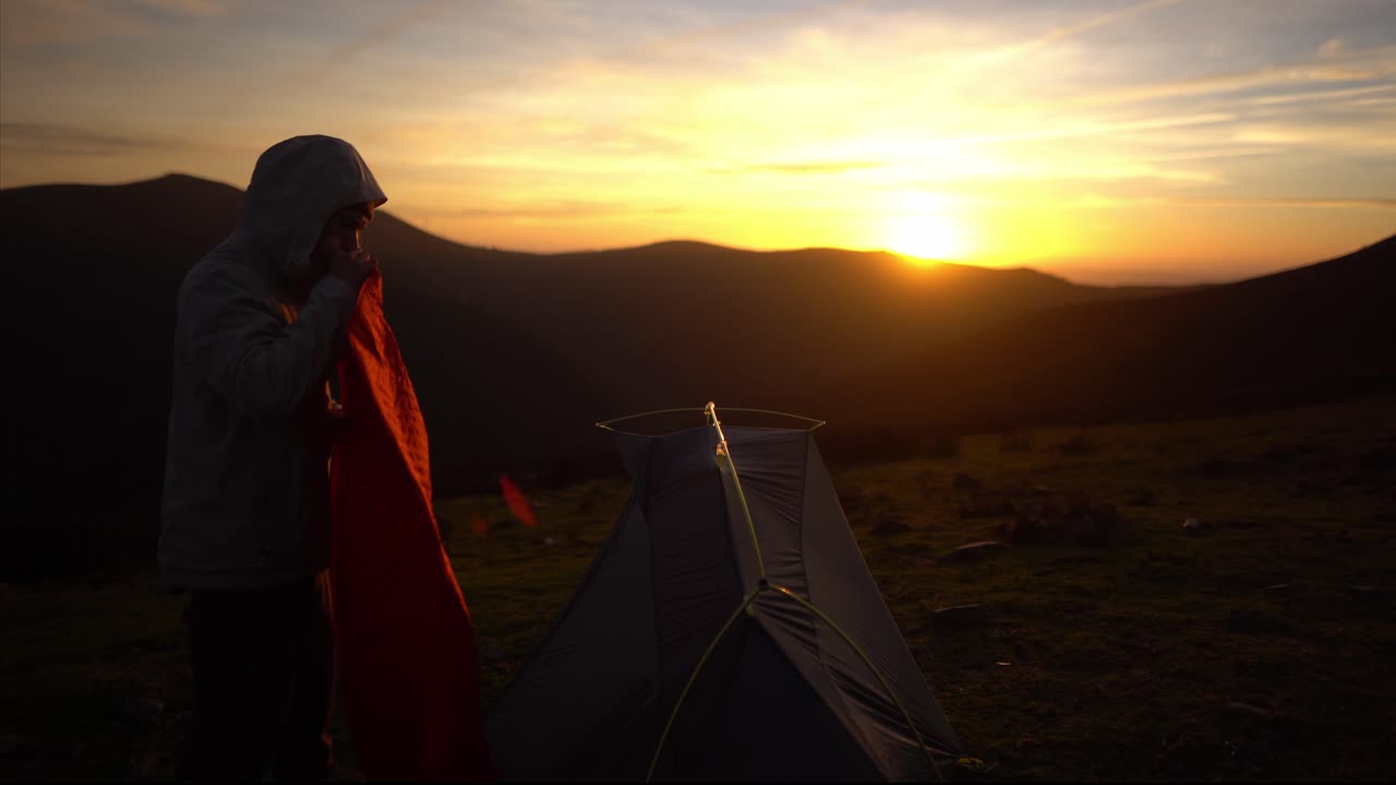 un joven excursionista prepara una tienda de campaña para acampar en la naturaleza al atardecer