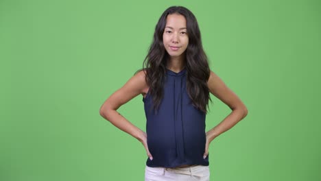 임신 중인 젊은 다민족 사업가 여성이 이에 손을 고 있습니다.