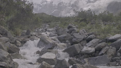 tilting up shot of a powerful river flowing down the mountain near the humantay lake peru log