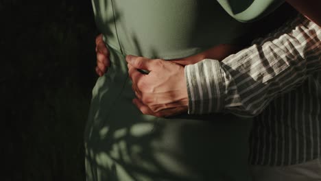 close view of arms holding waist tenderly in warm natural shadows