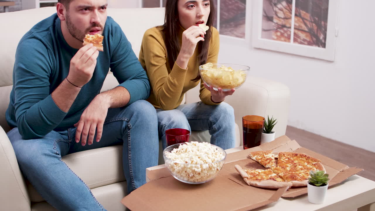 Couple Watching TV and Eating Snacks at Home