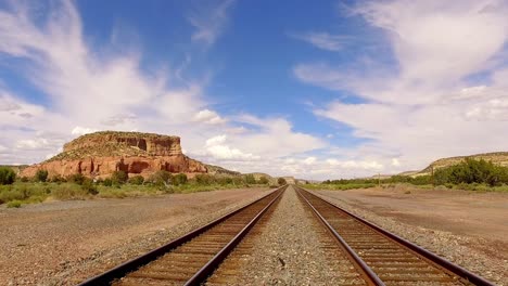 camera pullinb back and scanning slowly of to the right rail road tracks of into the distance in the arizona desert blue skies and puffy white clouds