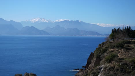 安塔利亚的岩石悬崖,树木和楼梯,风景优美的地中海和托罗斯山脉在后面