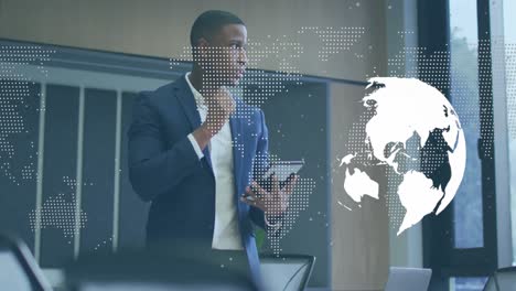 animation of spinning globe and world map over african american businessman using digital tablet