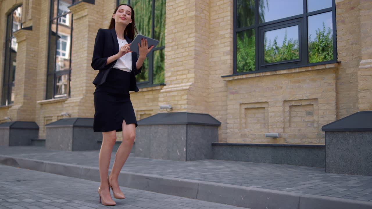 mujer de negocios caminando al trabajo. mujer de traje usando tableta digital en la calle de la ciudad.