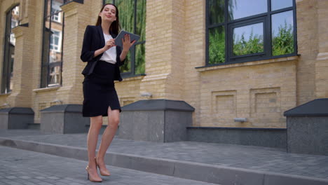 Businesswoman-walking-to-work.-Suit-lady-using-digital-tablet-on-city-street.