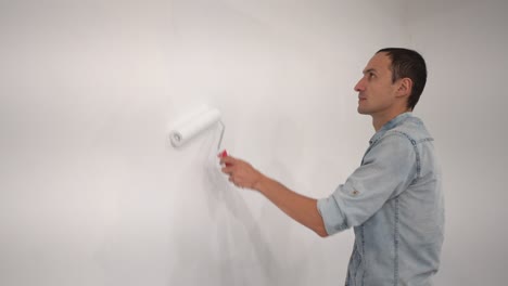 male decorator painting a wall with white color.