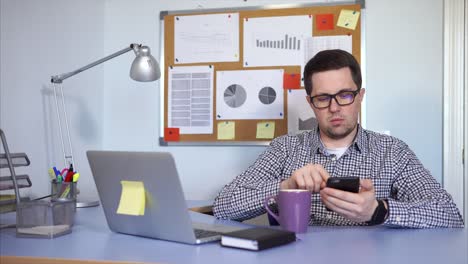 hombre trabajando en su escritorio con café y portátil.