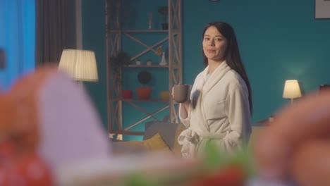 woman in bathrobe drinking coffee