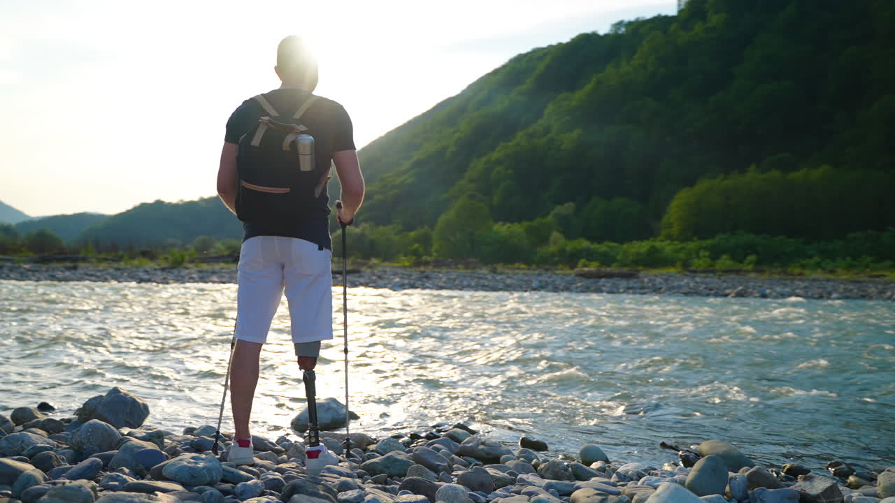 hombre con pierna protésica caminando en las montañas por el río