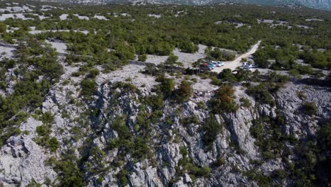 Una-Cautivadora-Vista-Desde-Un-Dron-Del-Mirador-Cerca-De-Paklenica,-Las-Montañas-Velebit-De-Croacia,-Con-Acantilados,-Automóviles-Y-Una-Exuberante-Flora-Mediterránea-Bajo-El-Sol-De-Verano.