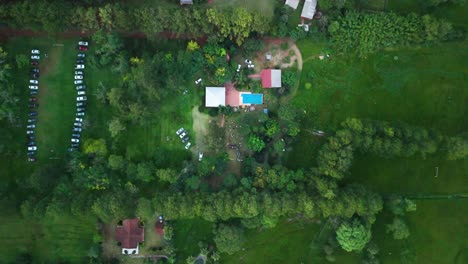 top-down zoom out drone shot of the farmhouse with visitors cars parked at a farmhouse